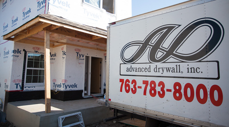 Advanced Drywall truck in front of a house under construction